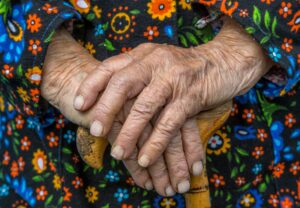 Image of an old person's hands, held over a walking stick